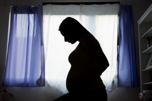 Silhouette of pregnant woman displaced in a temporary bedroom