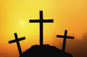 Silhouettes of Three Crosses on hill at sunset